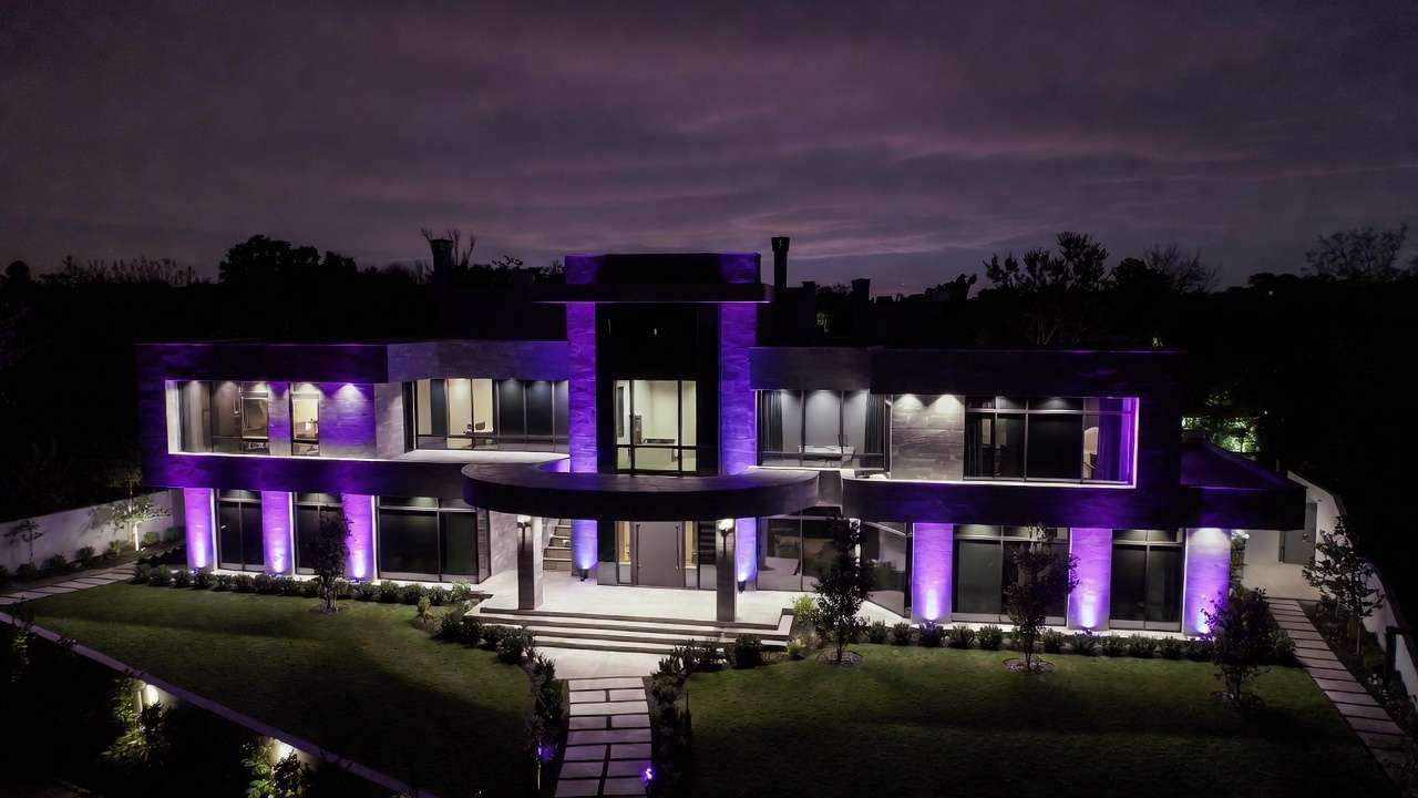 Modern villa at night, purple LED lighting on facade